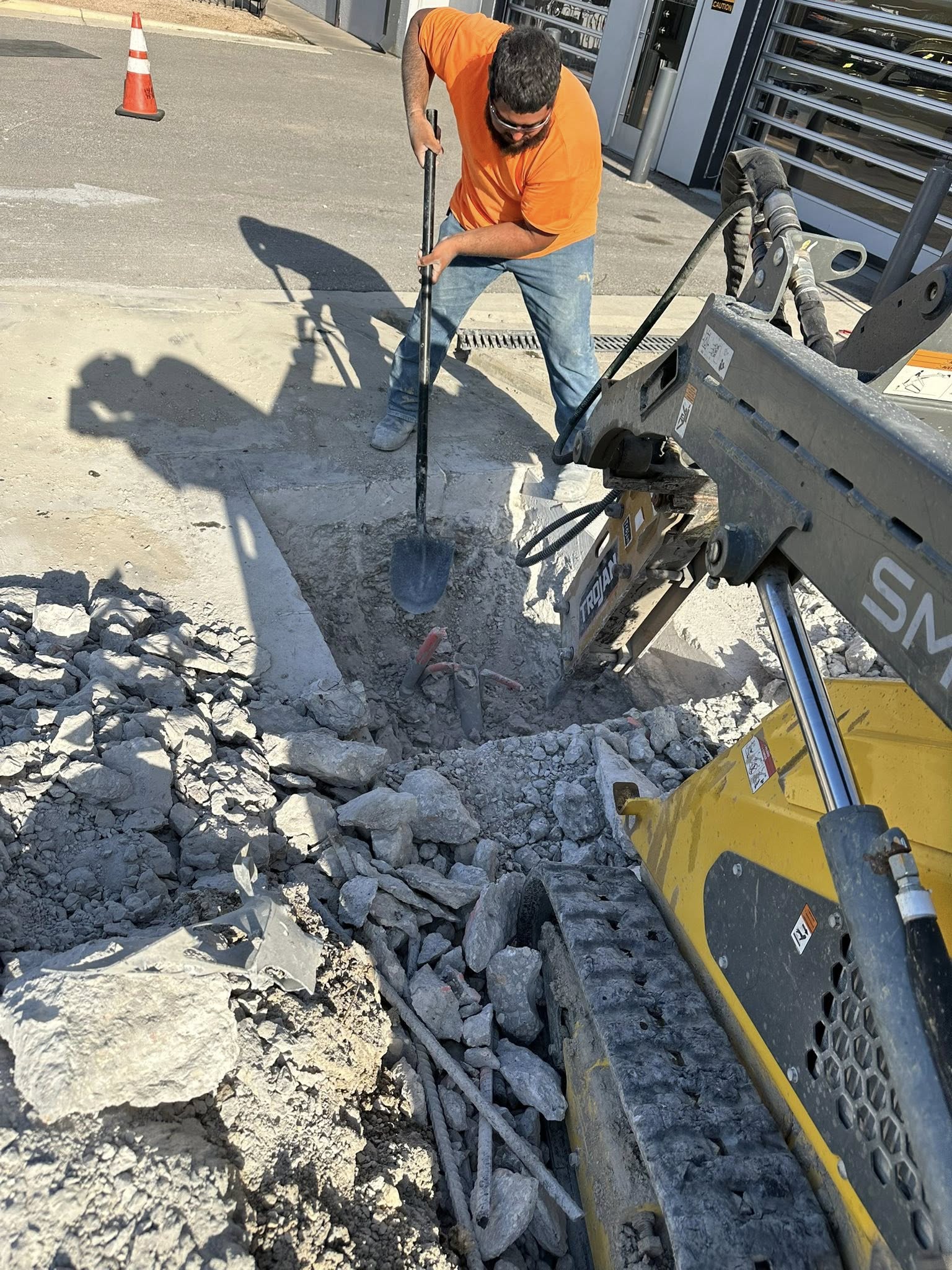 Worker breaking concrete with jackhammer inside pit